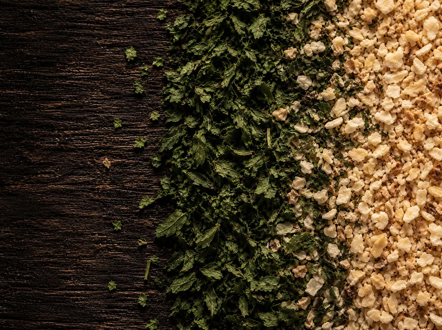 Macro cenital de la mezcla seca de provenzal: hojuelas verdes de perejil a la izquierda, gránulos beige de ajo deshidratado a la derecha y la franja donde las dos granulometrías se encuentran.